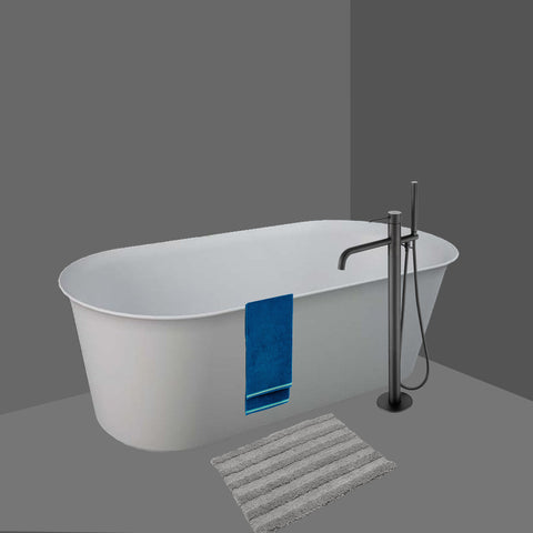 Brushed Black floor standing bath tap next to a free standing bath tube and a towel hanging on the bath tube.