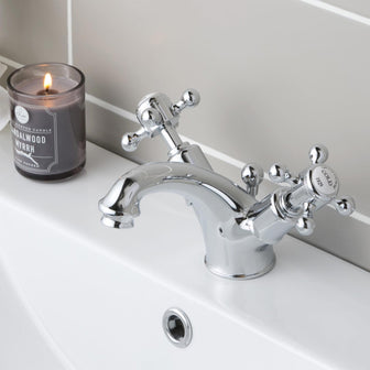 Two handles crosshead  basin mixer tap installed on a basin with a burning candle next to it Main image