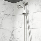 Shower rail kit with traditional handset fixed in a shower bracket installed on a white tilled bathroom wall 