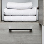 Double door bathroom side cabinet in grey with one door open showing towels on the shelve 