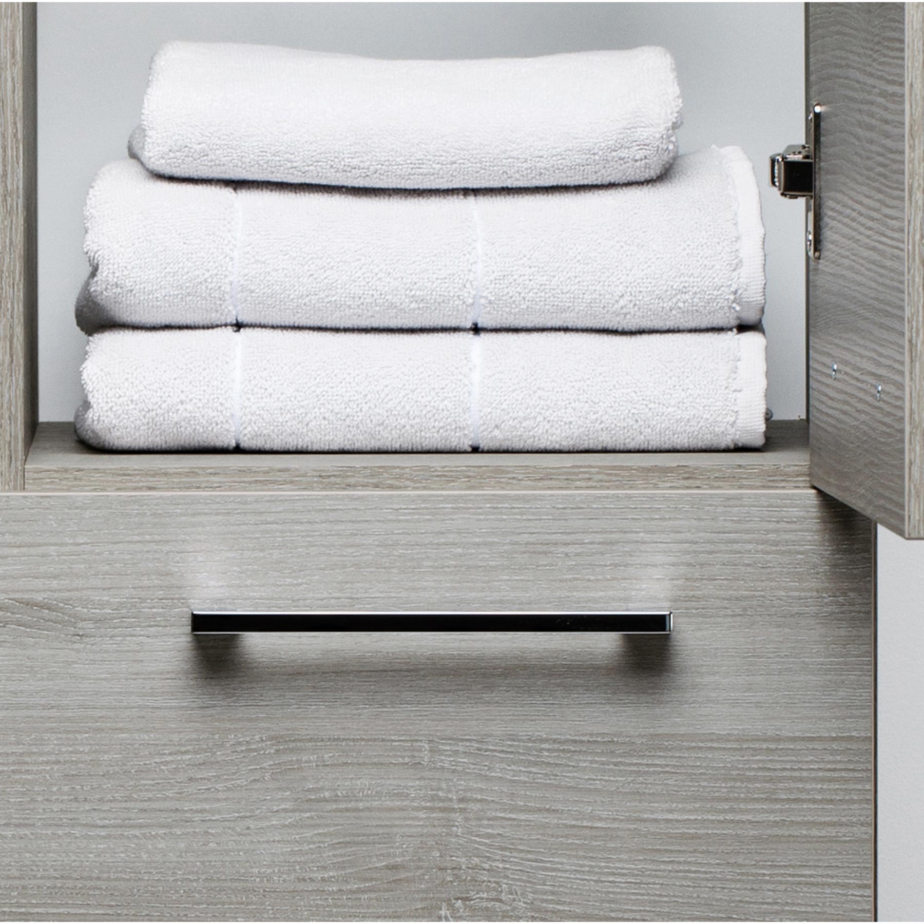 Double door bathroom side cabinet in grey with one door open showing towels on the shelve 